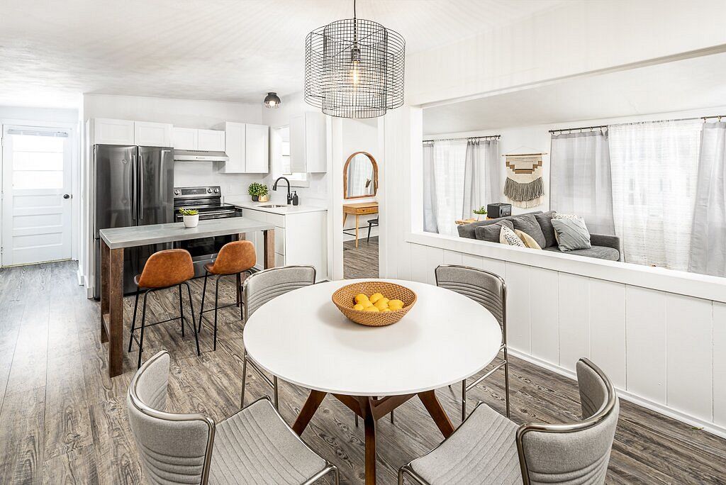Open-concept kitchen and dining area with round table, bar, and view into the living room.