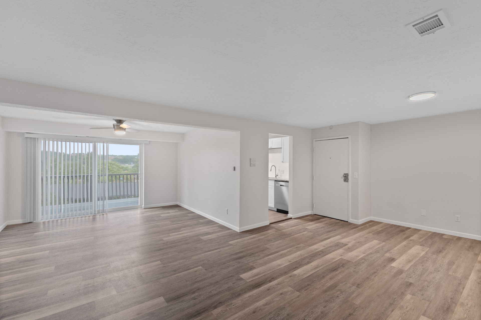 Large open-concept living space with wood-style floors and sliding patio doors.