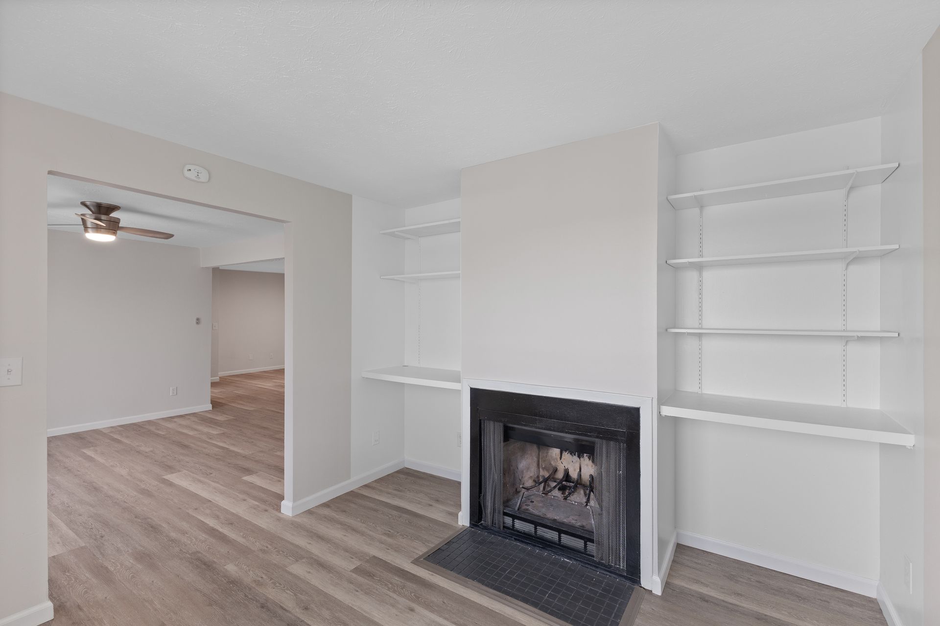 Apartment living room with fireplace, built-in shelving, and wood-style flooring.