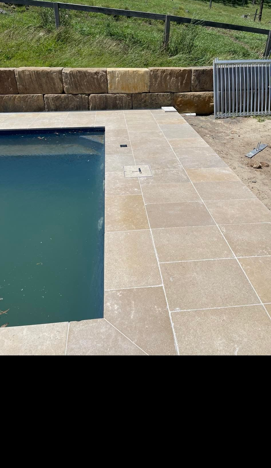 Poolside with sandstone pavers and retaining wall. — East Coast Paving in Seaham, NSW