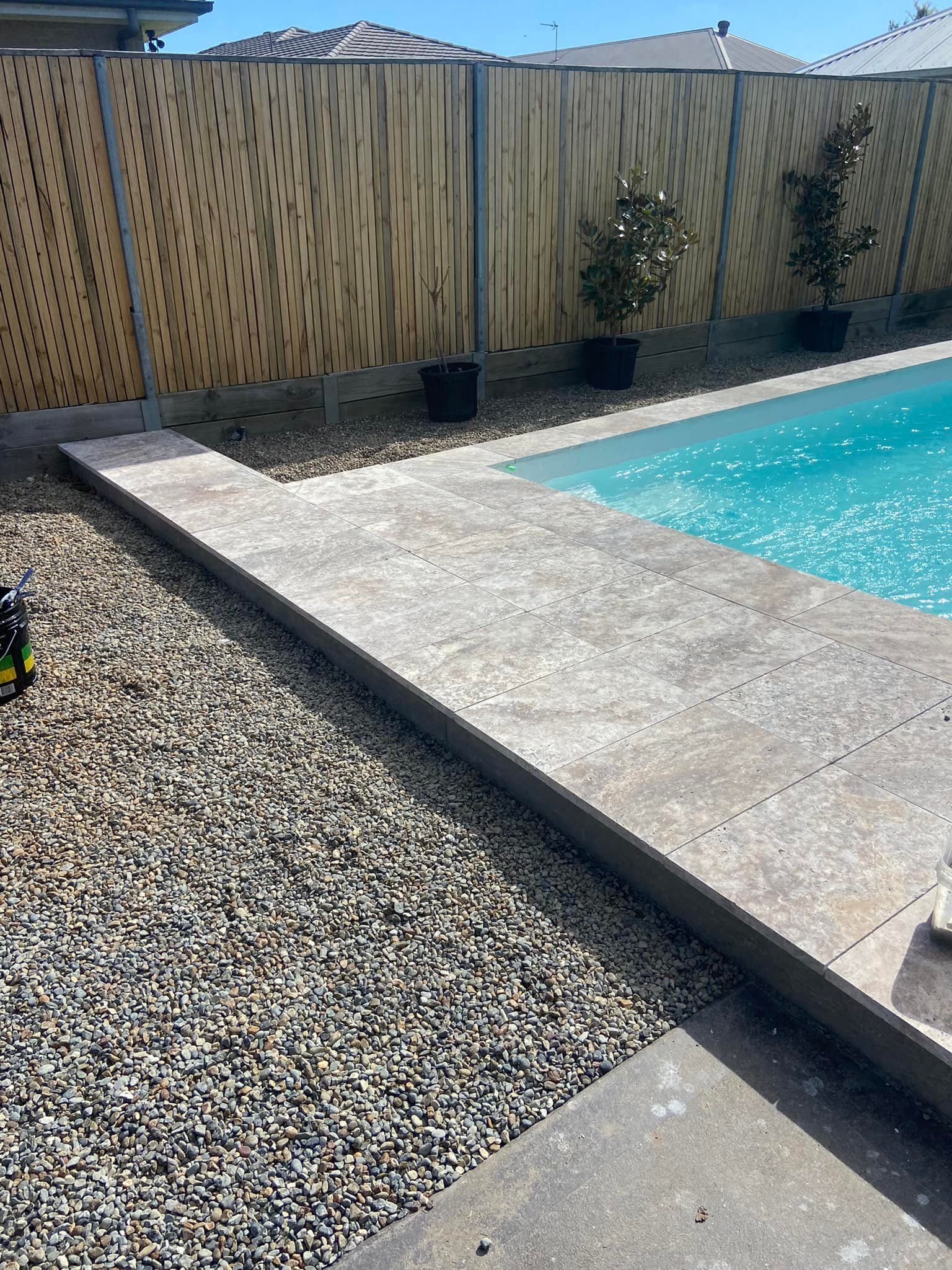 Poolside view with concrete path, gravel bed, and wooden fence. — East Coast Paving in Seaham, NSW