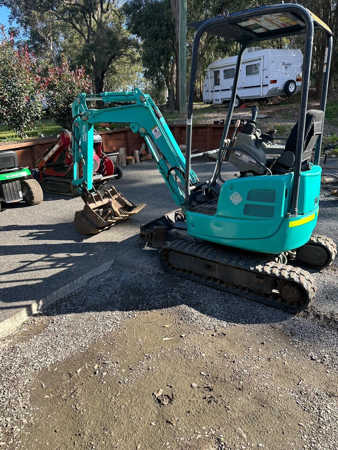 Turquoise mini excavator on gravel, parked outdoors. — East Coast Paving in Seaham, NSW