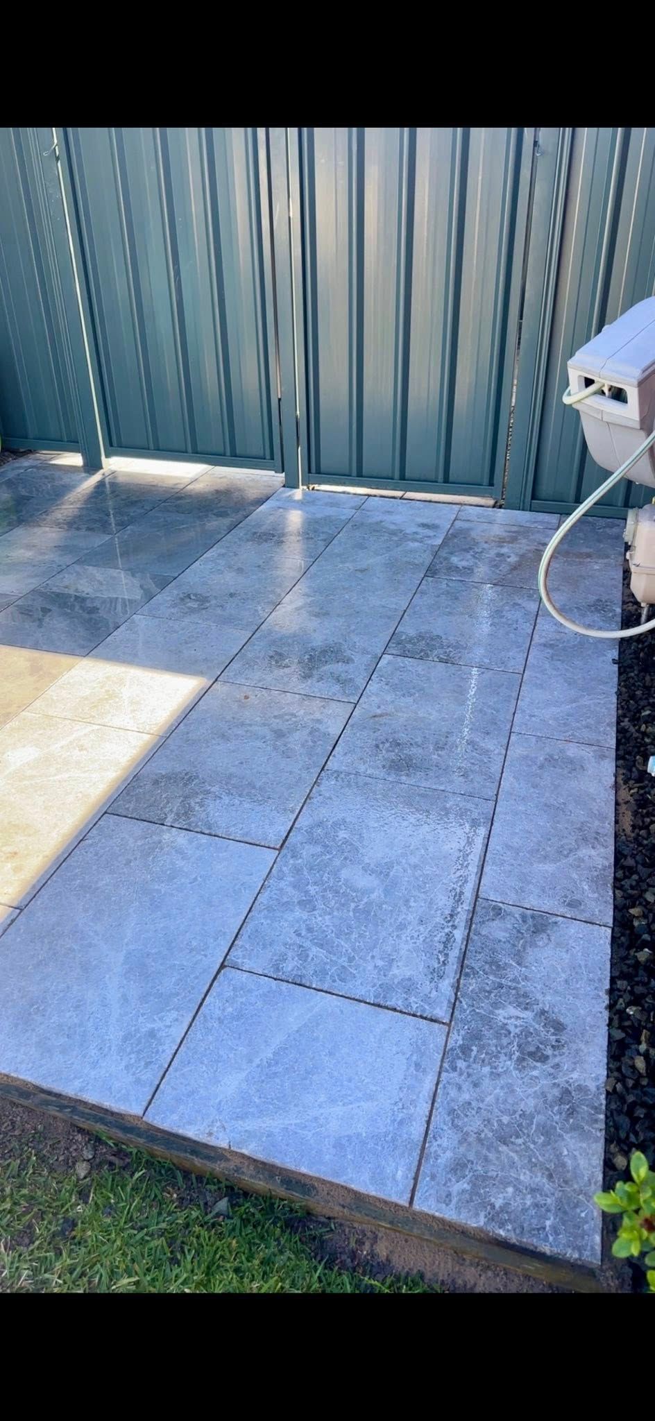 Paved walkway leading to a metal fence; sunlight casts shadows on the paving stones, with grass and landscaping. — East Coast Paving in Seaham, NSW