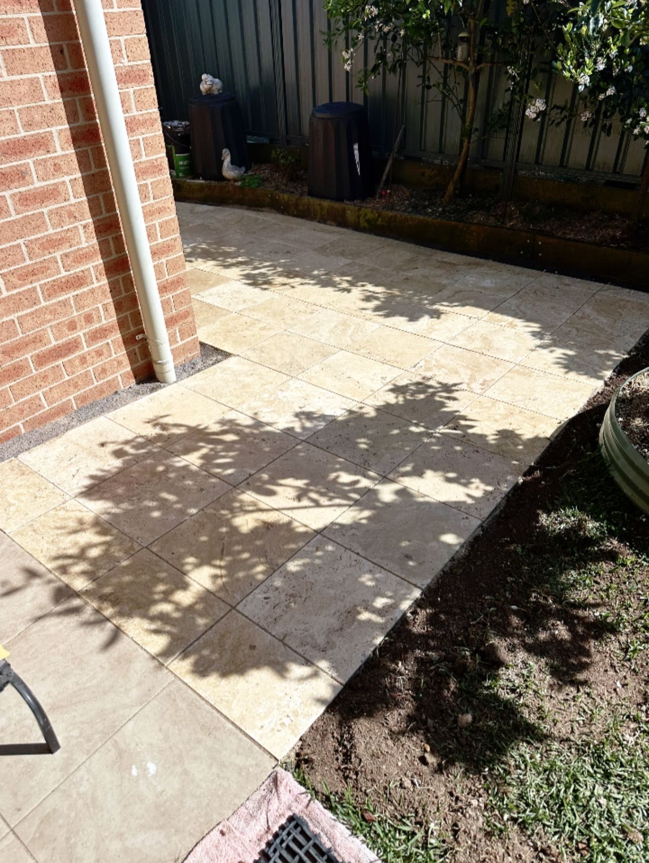 Patio pavers next to a brick wall with tree shadows on a sunny day. — East Coast Paving in Seaham, NSW
