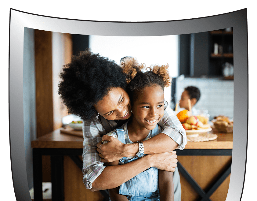 A woman is hugging a little girl in a kitchen.