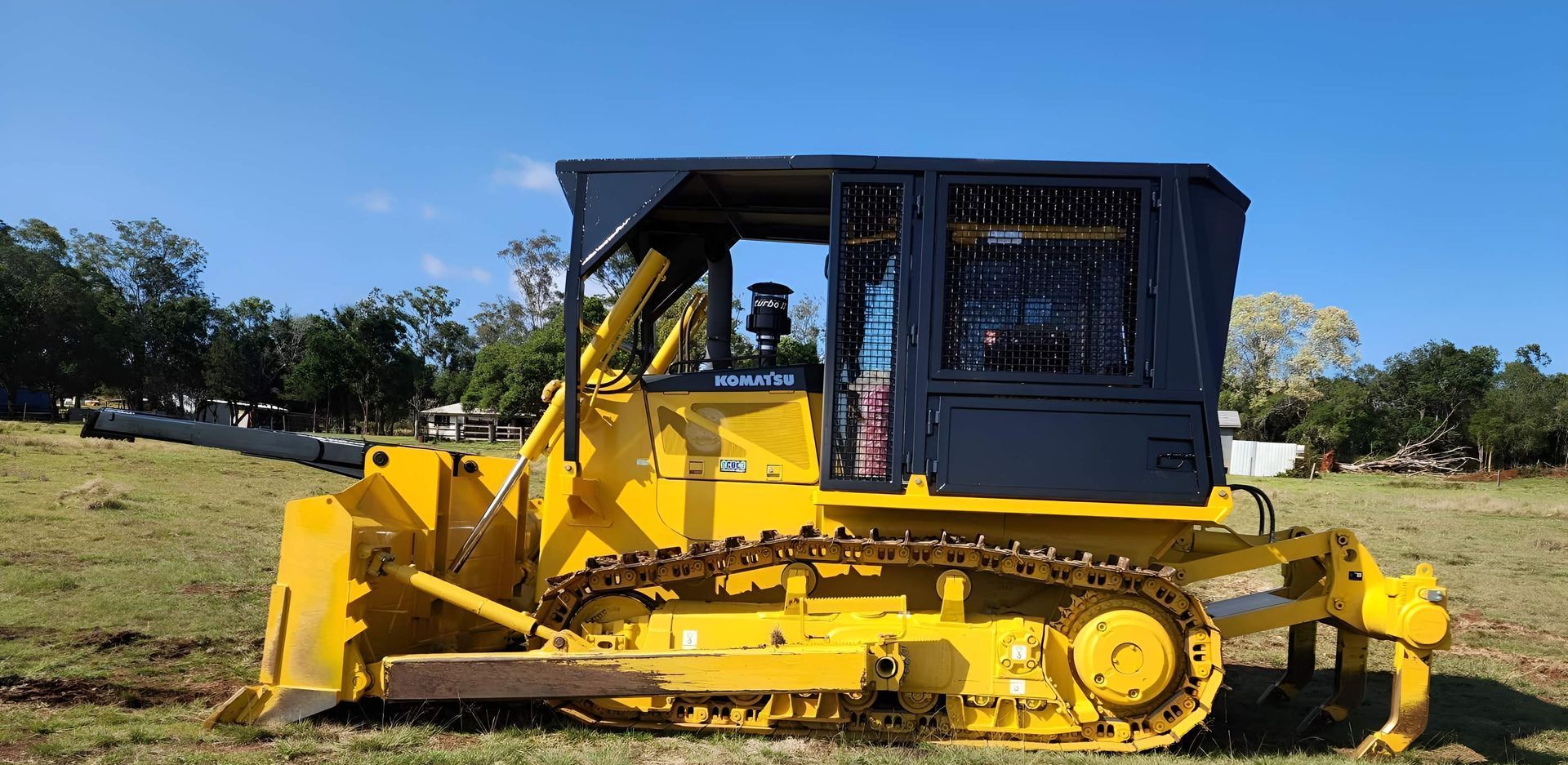 A Man Is Holding A Dog While Sitting On A Cat Bulldozer — Greenslade's Dozer & Excavator Hire Pty Ltd In Taabinga, QLD