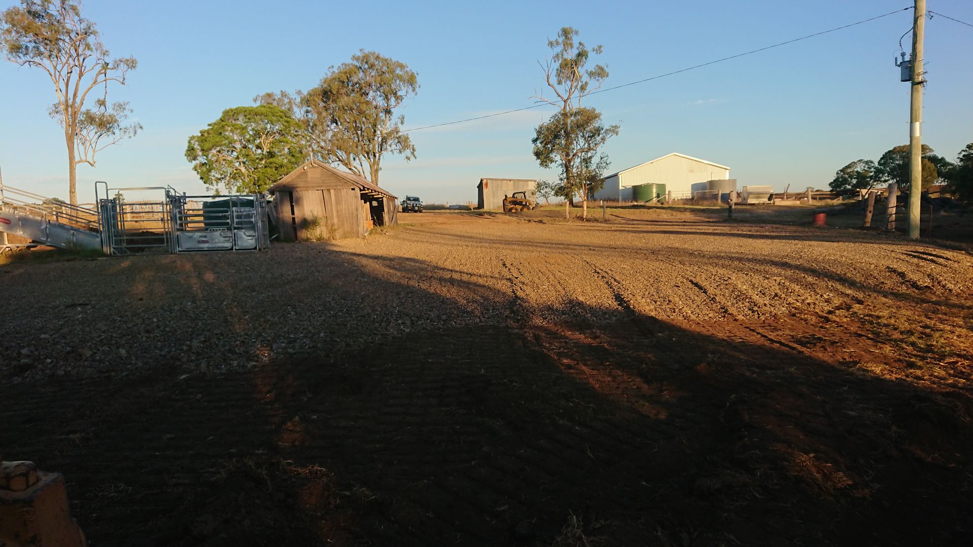 A Wooden Shed Next To A Bobcat and Metal Shed — Greenslade's Dozer & Excavator Hire Pty Ltd In Taabinga, QLD