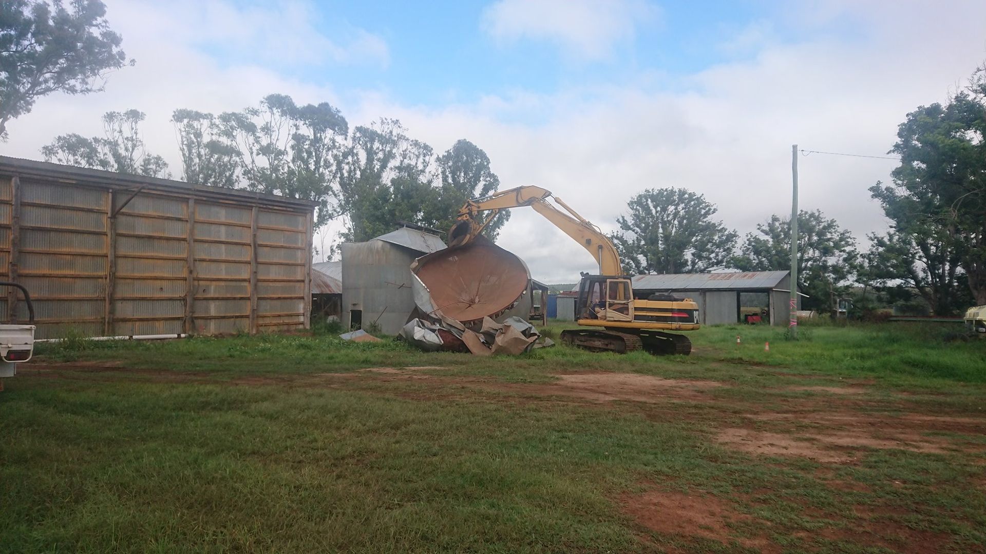 An Excavator Removing A Metal Shed — Greenslade's Dozer & Excavator Hire Pty Ltd In Taabinga, QLD