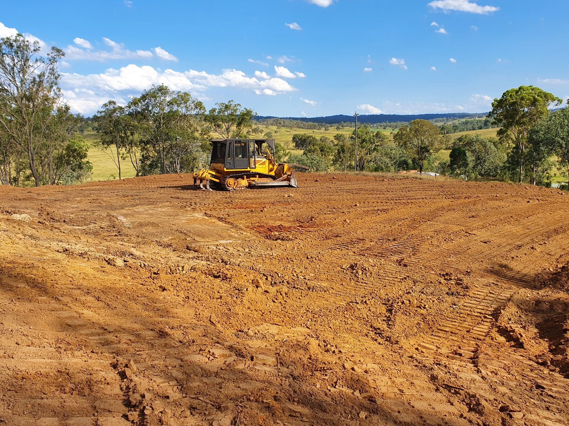 A Yellow Tractor Cleaning House Pads — Greenslade's Dozer & Excavator Hire Pty Ltd In Taabinga, QLD