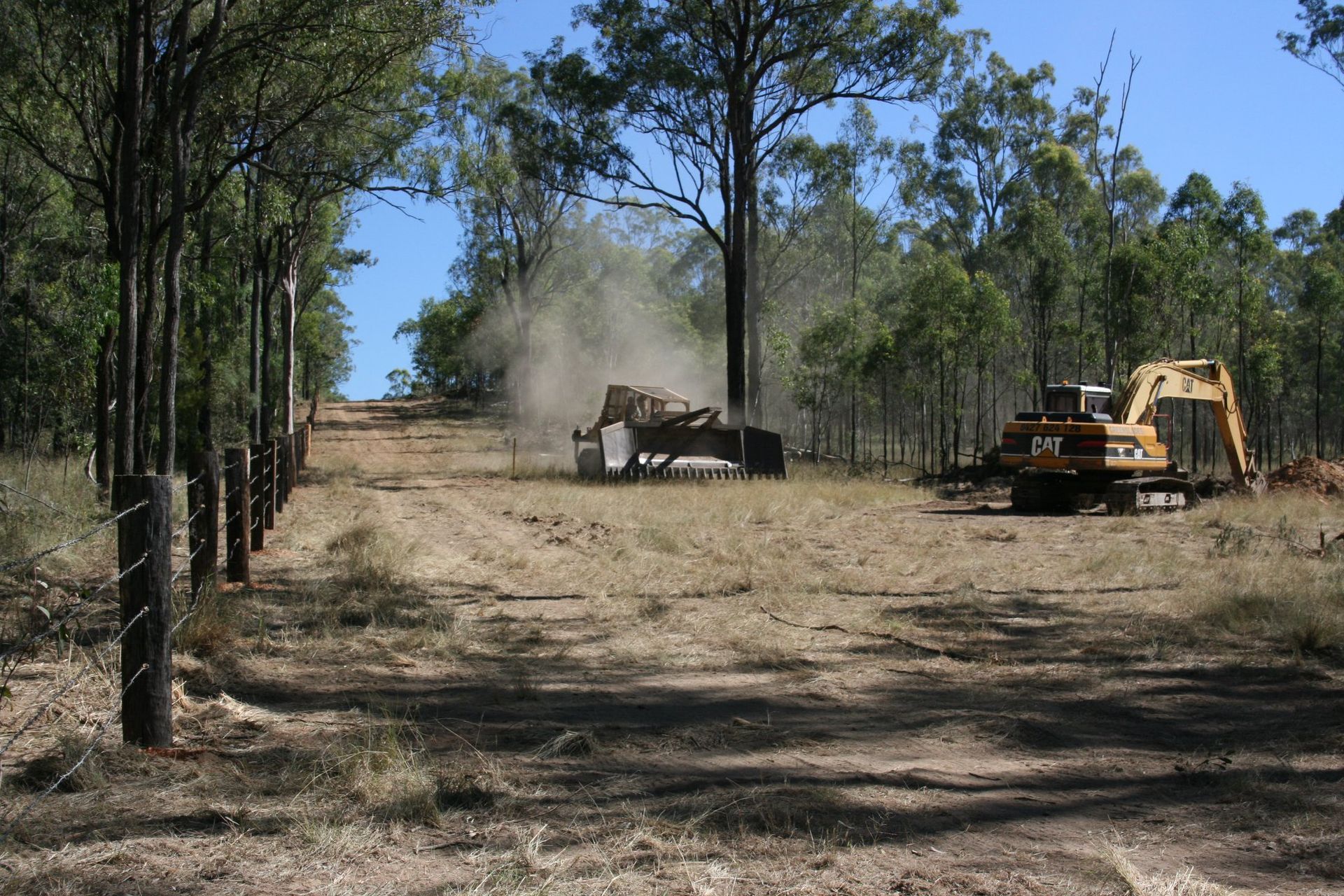 A Yellow Truck Is Clearing Fence — Greenslade's Dozer & Excavator Hire Pty Ltd In Taabinga, QLD