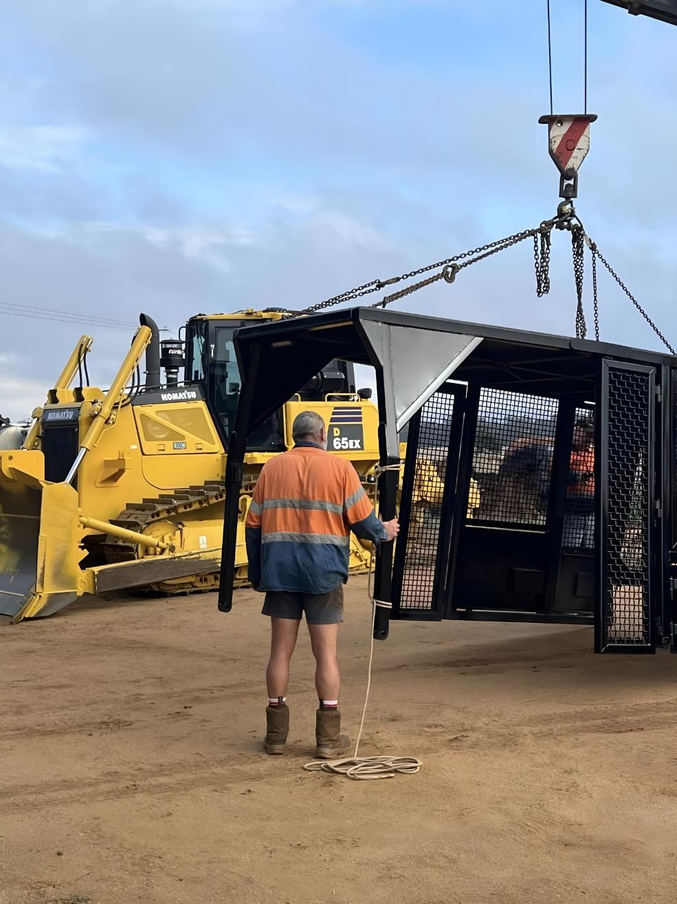 A Man Is Standing In Front Of A Bulldozer — Greenslade's Dozer & Excavator Hire Pty Ltd In Taabinga, QLD