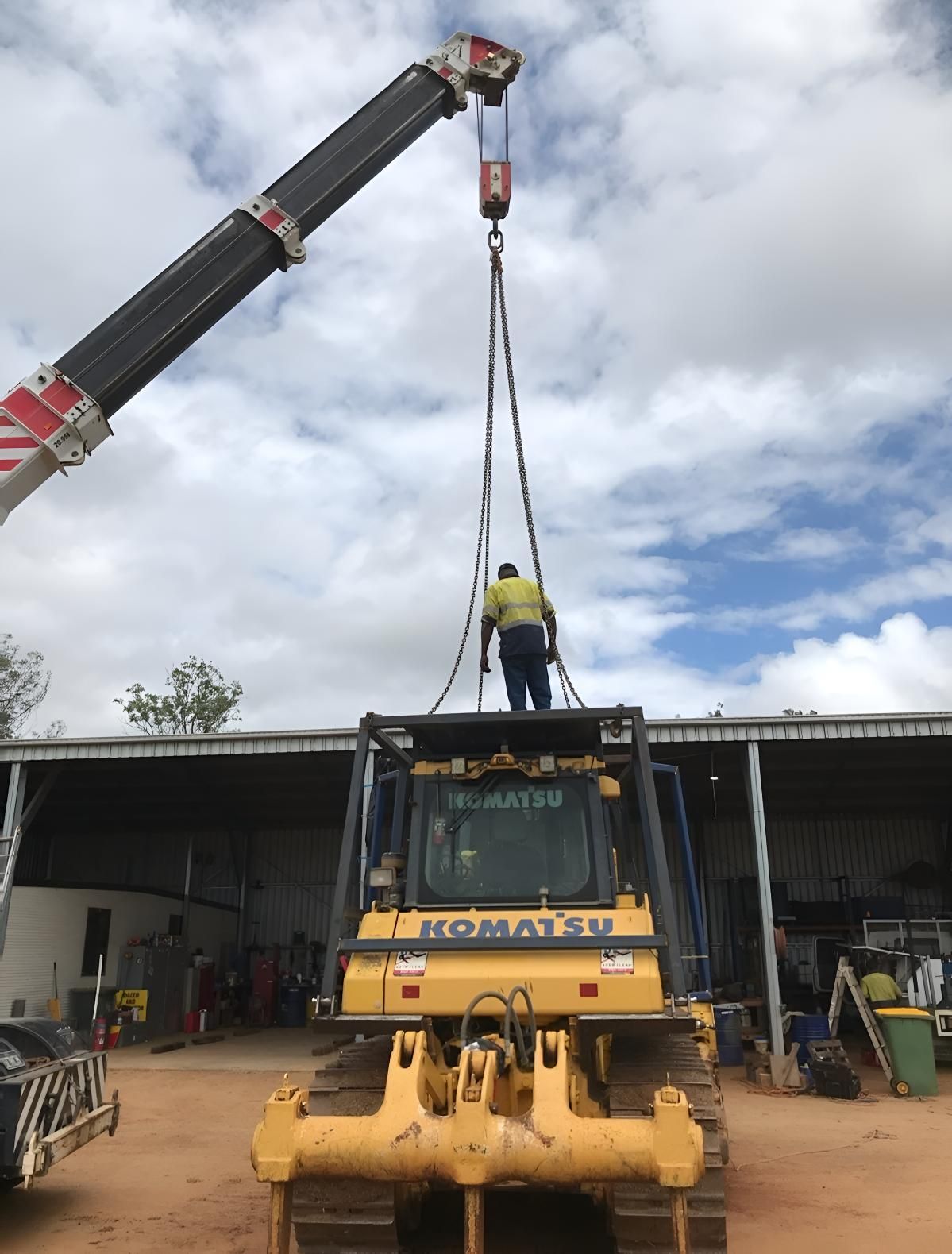 A Man Is Standing On Top Of A Komatsu Bulldozer — Greenslade's Dozer & Excavator Hire Pty Ltd In Taabinga, QLD