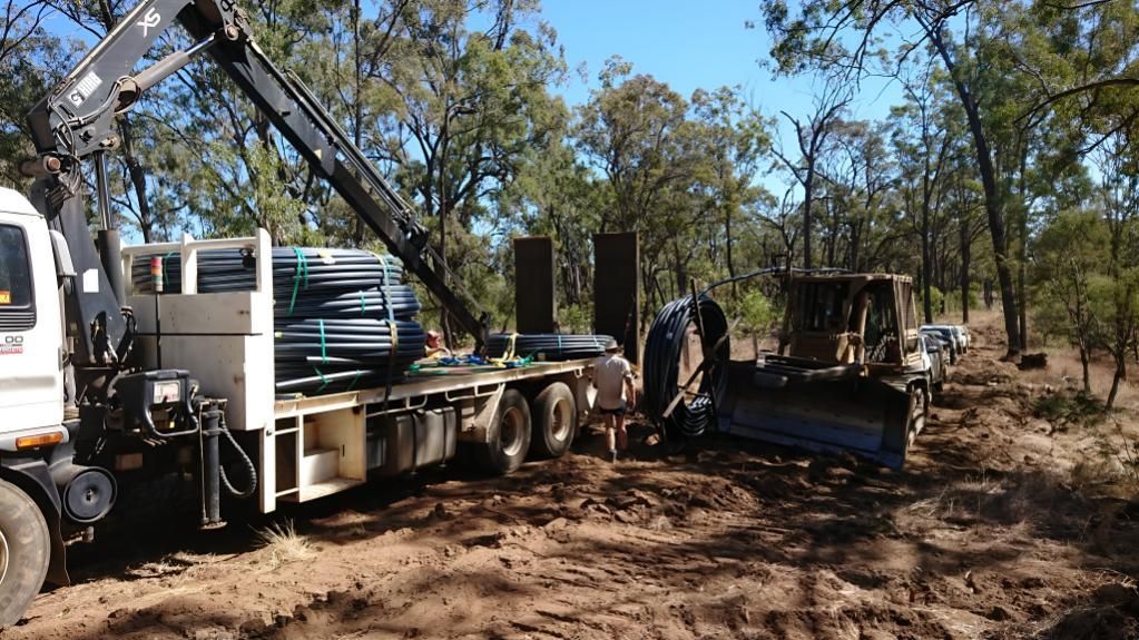 A Truck Is Laying A Pipe In A Trench — Greenslade's Dozer & Excavator Hire Pty Ltd In Taabinga, QLD