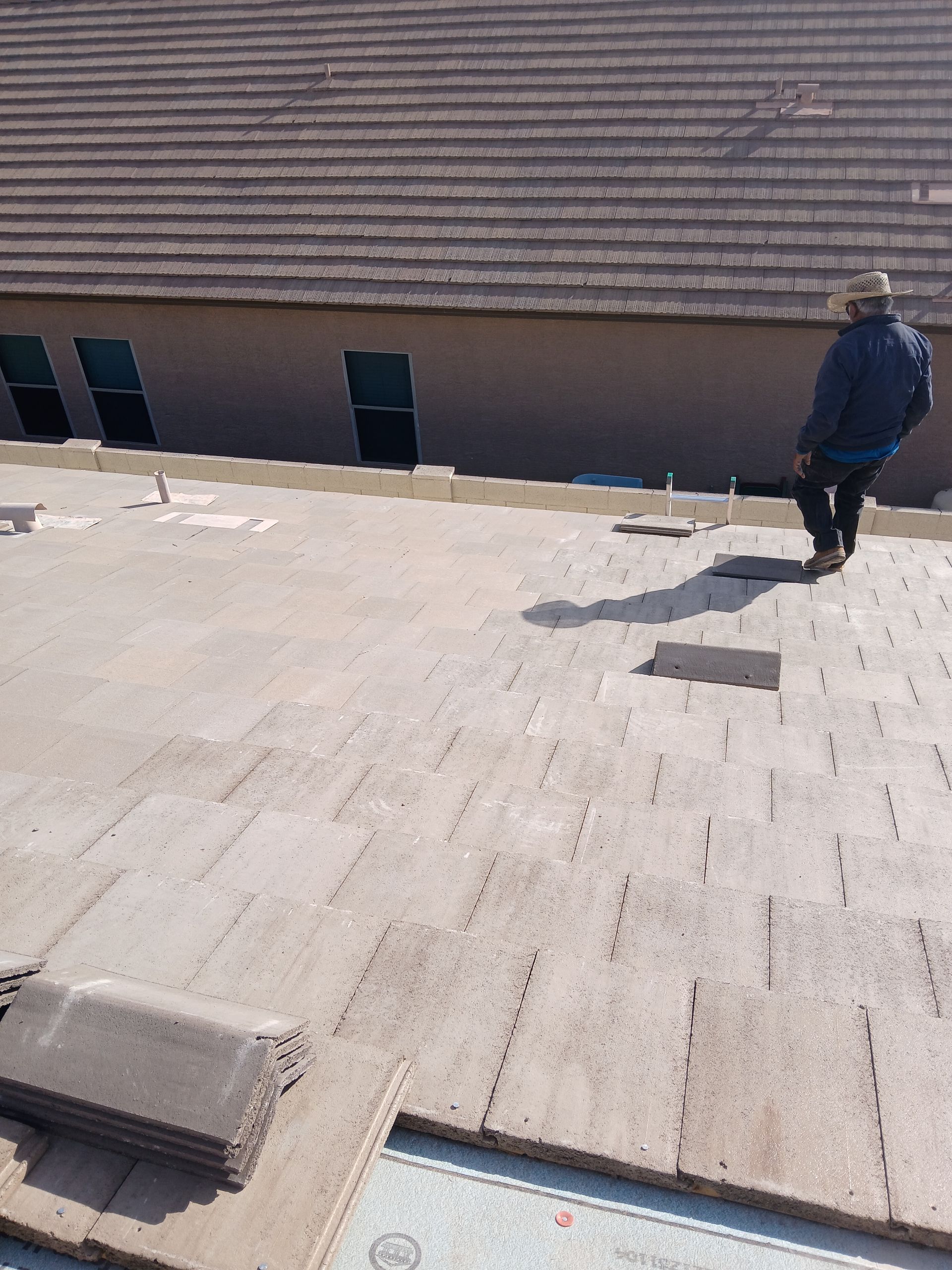 Person on a roof with removed tiles, preparing for roof repair.