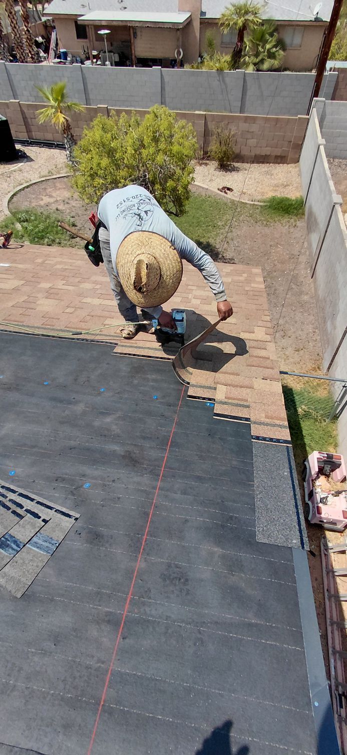 A worker wearing a straw hat is cutting brick pavers in a yard.