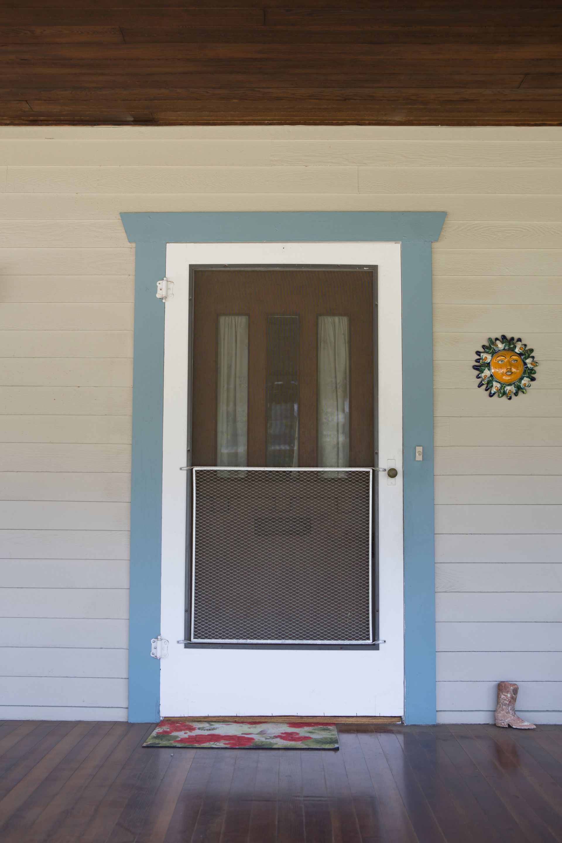 A screen door with a wreath on the wall above it