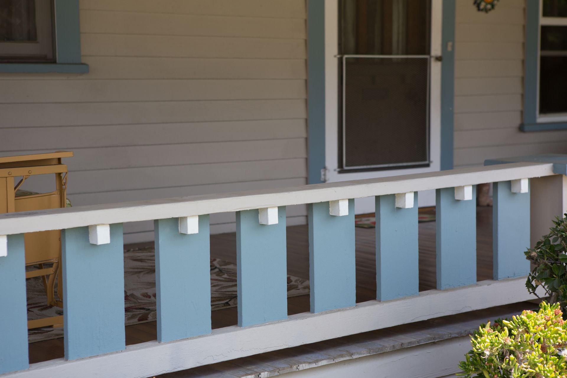 A porch with a blue railing and a screen door
