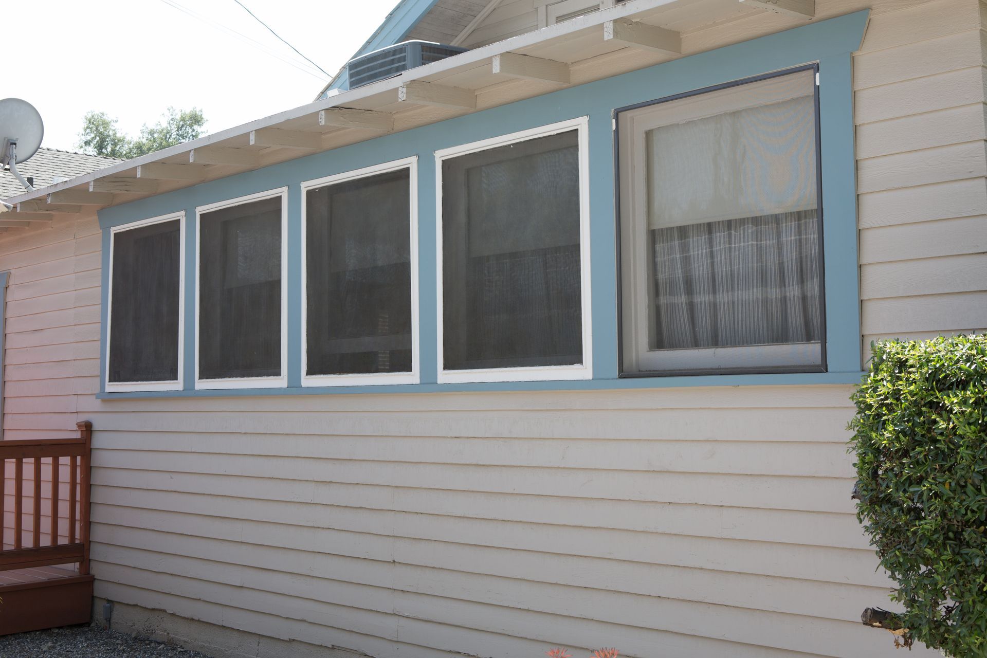 A white house with blue trim and screened in windows