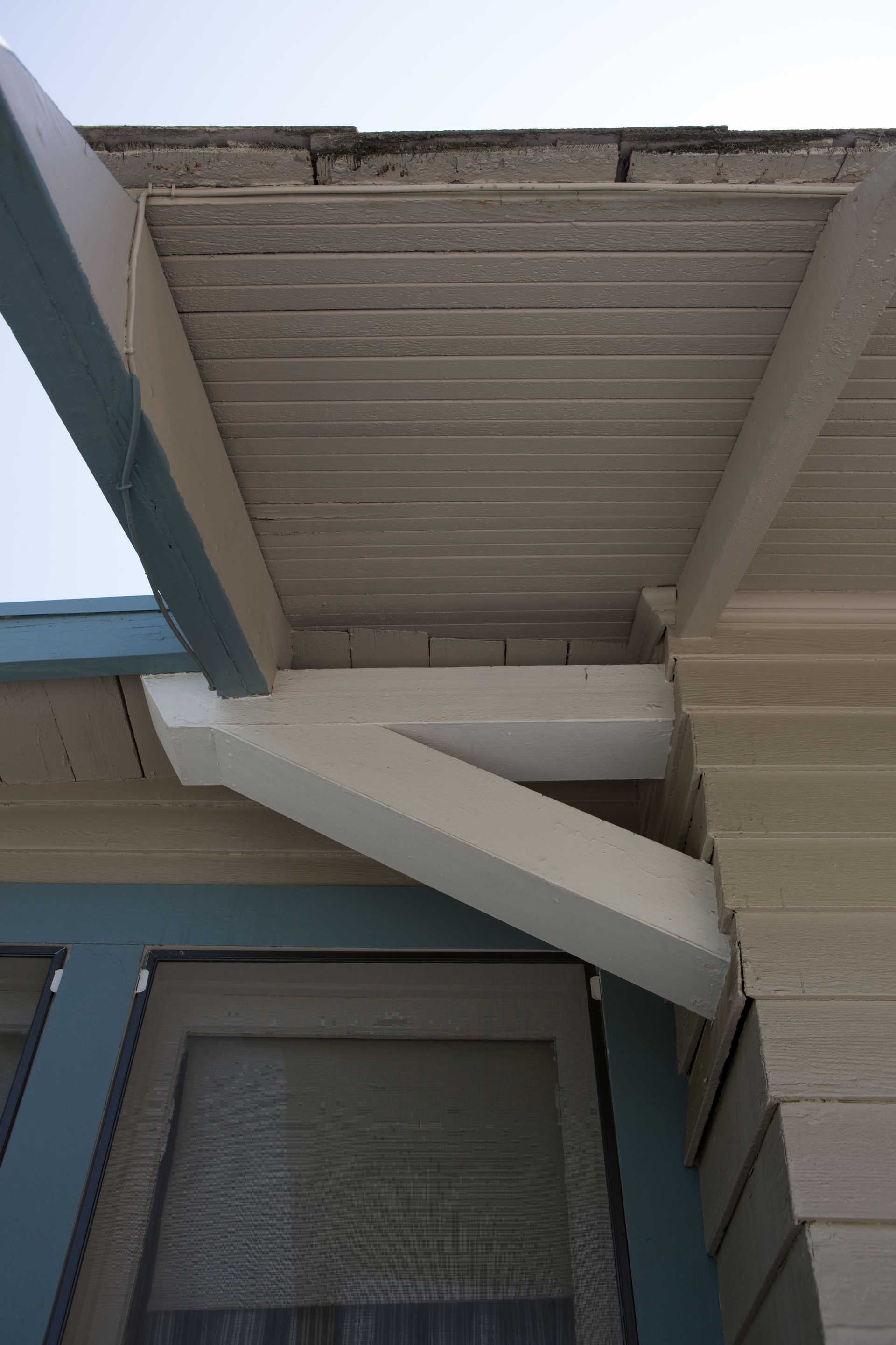The roof of a house with a blue trim and a white beam.