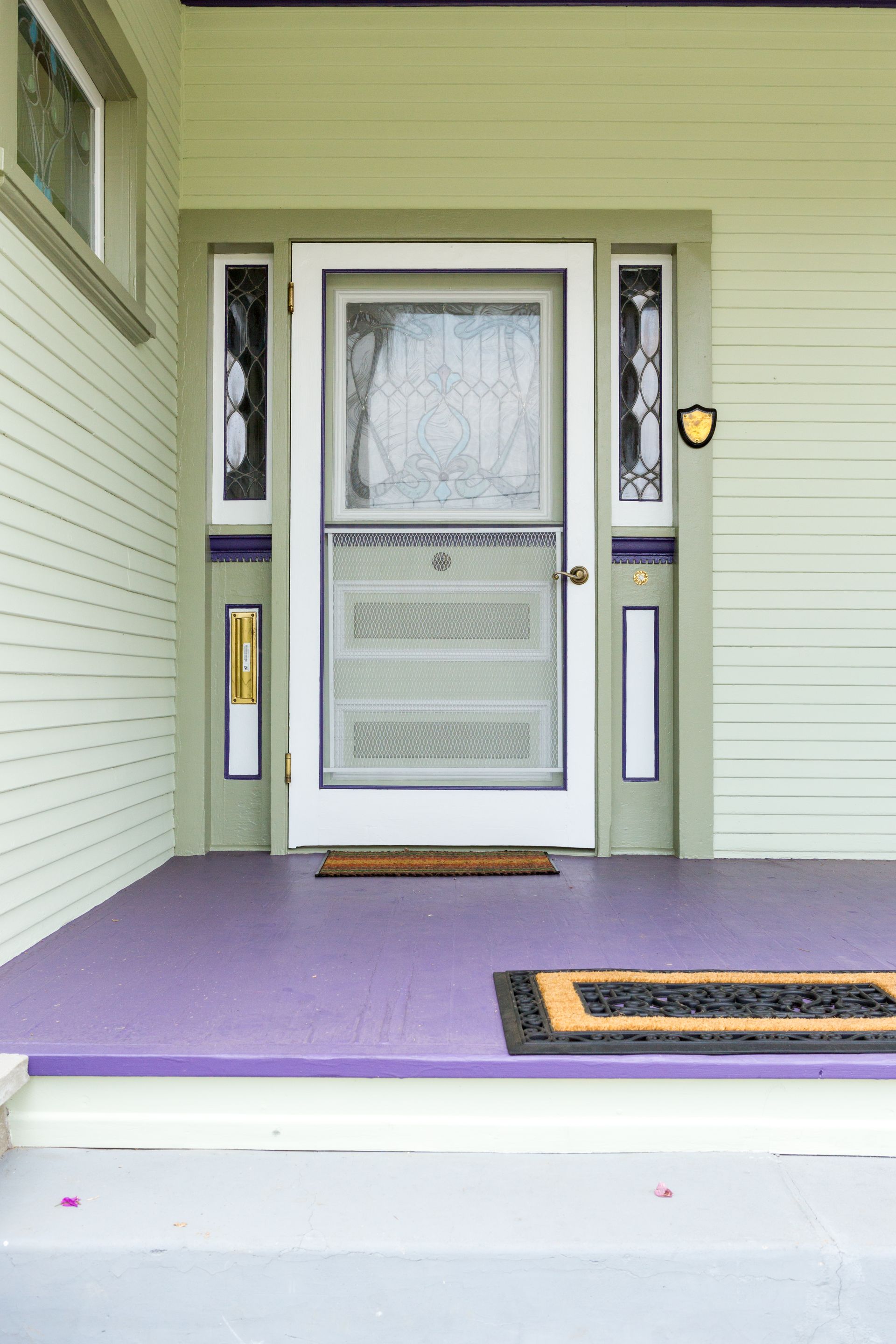 A purple porch with a white door and a welcome mat