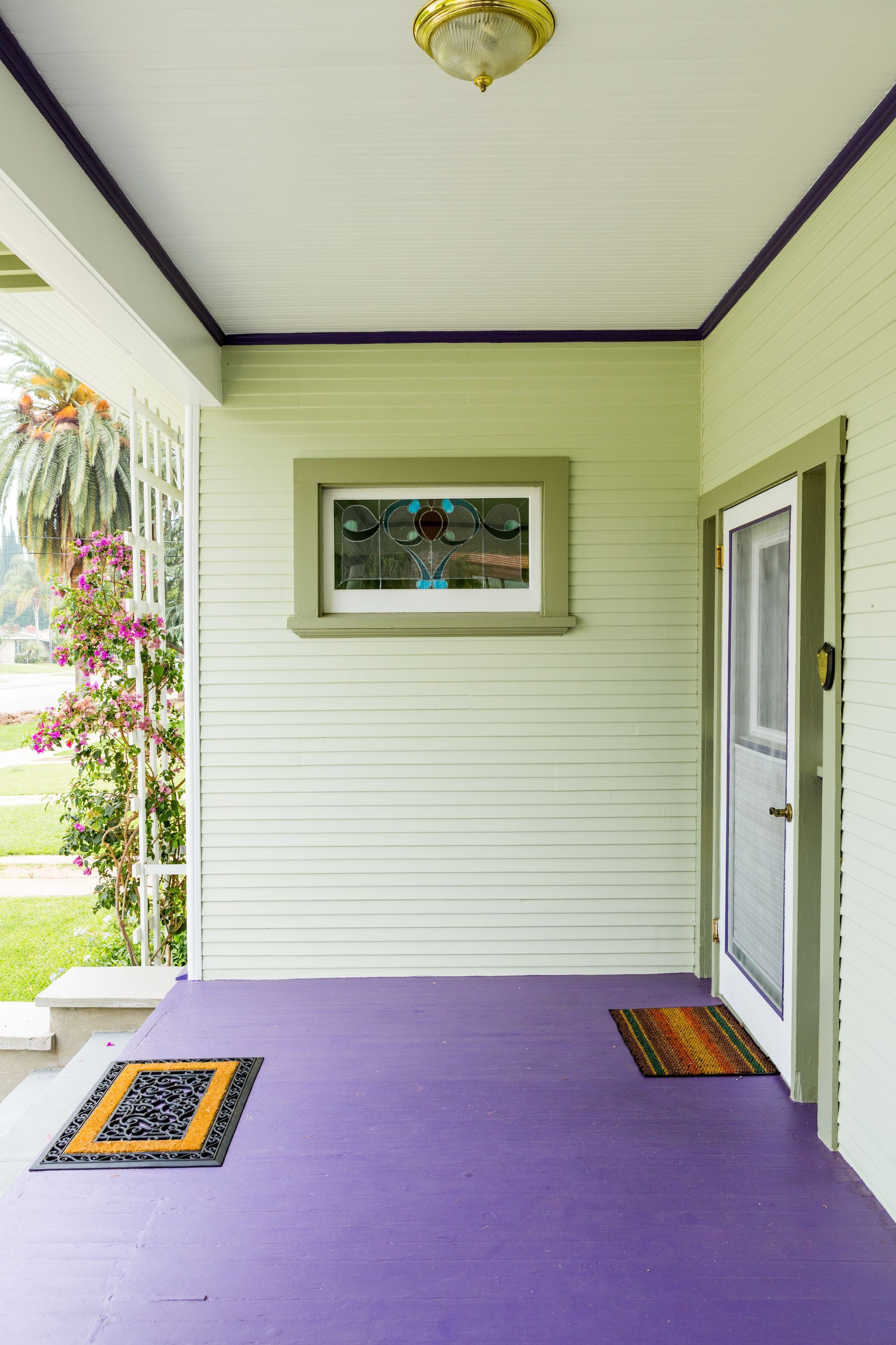 A porch with a purple floor and a stained glass window