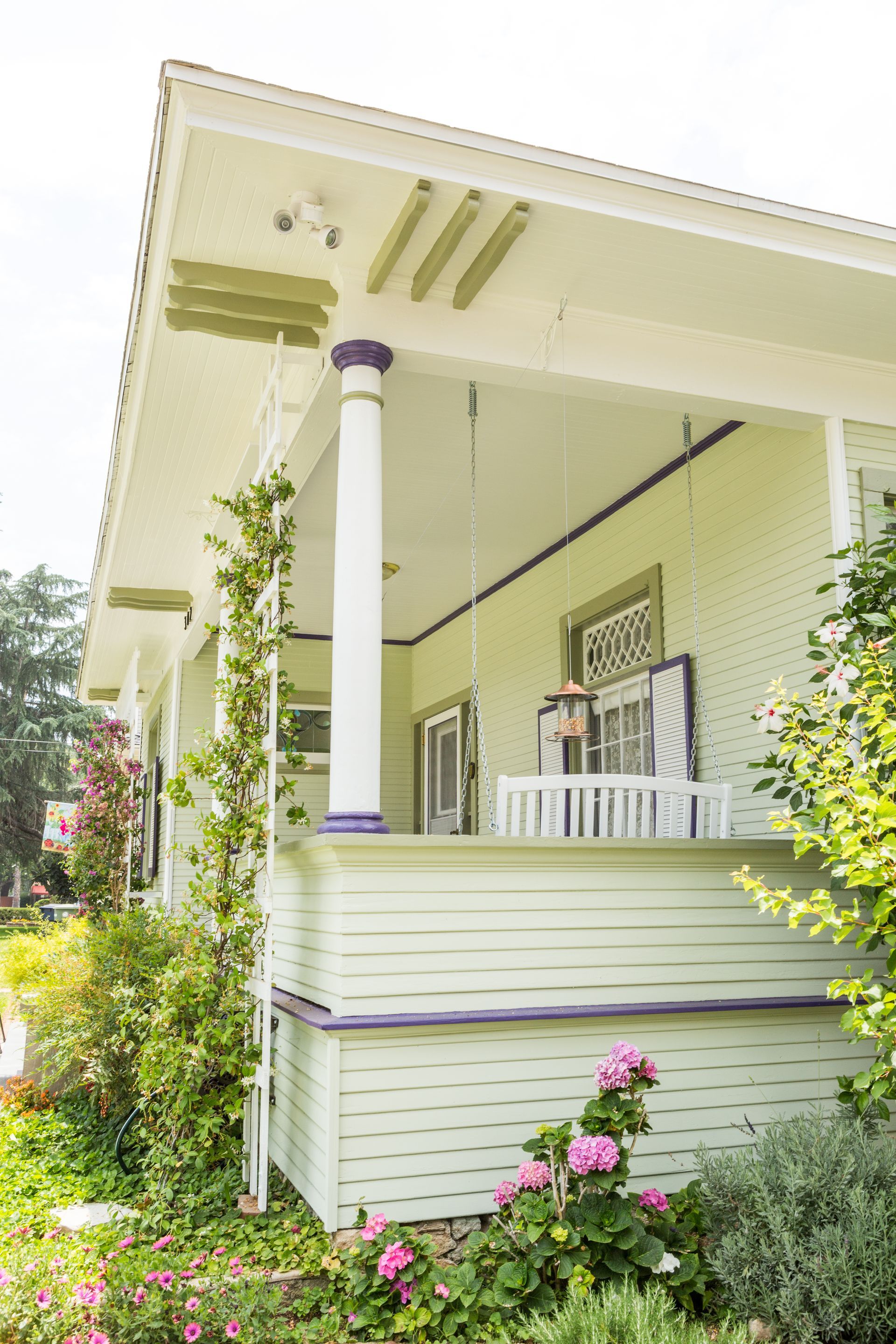 A white house with a porch and flowers in front of it.