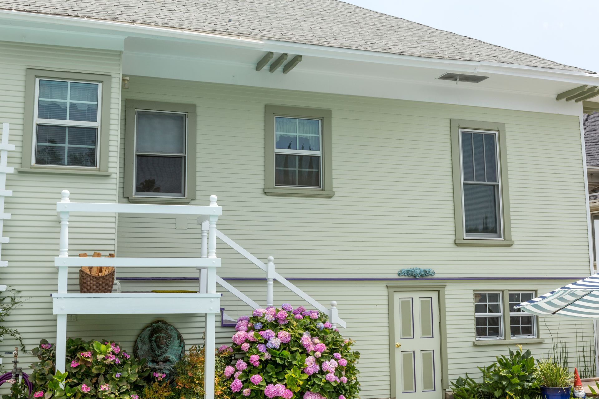 A white house with a balcony and flowers in front of it.