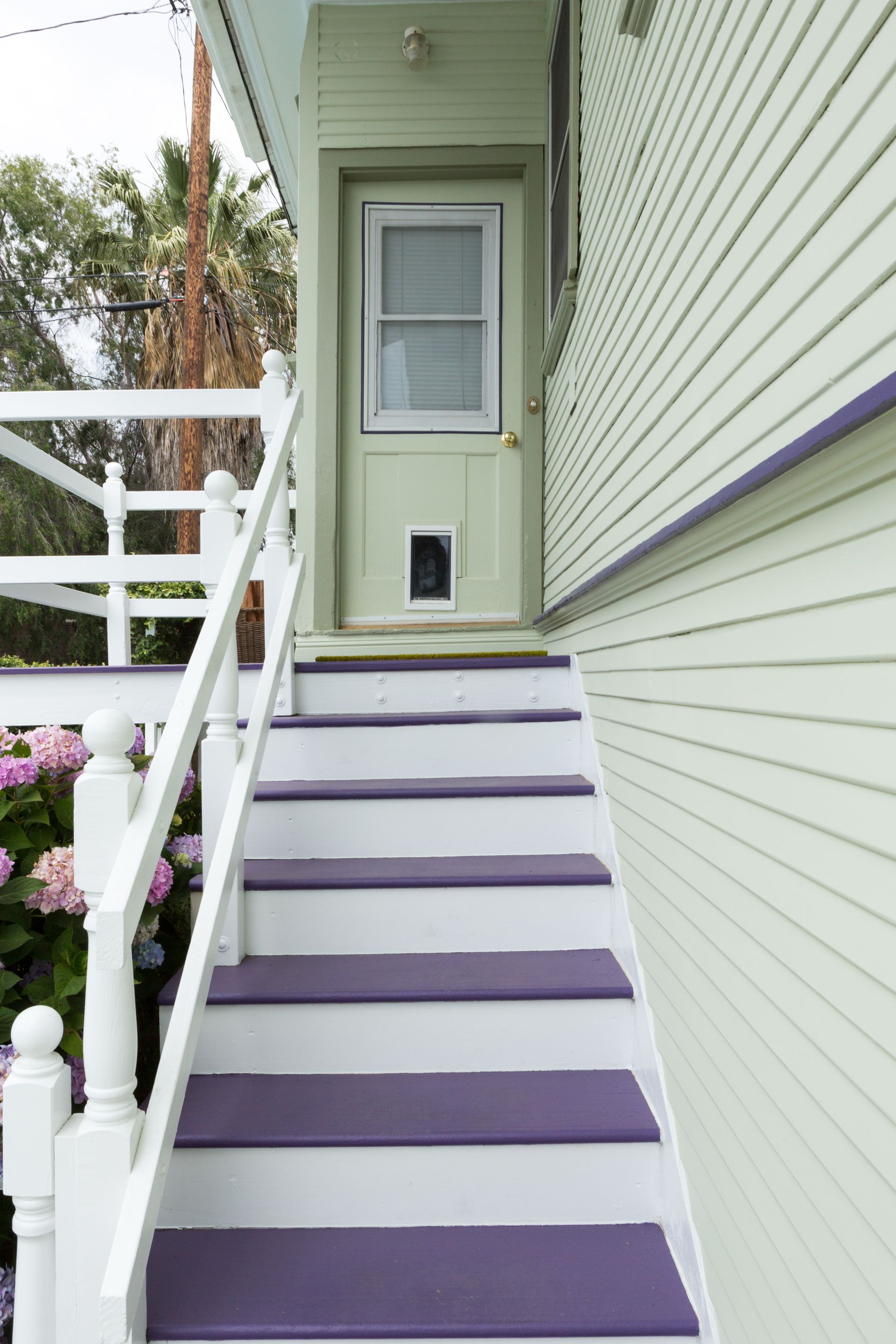 A white house with purple stairs leading up to it.