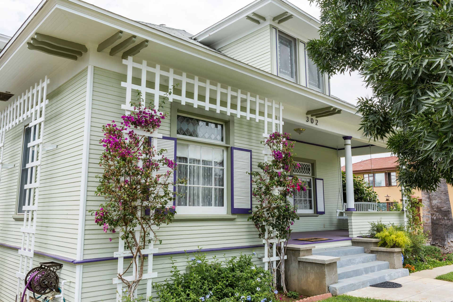 A white house with purple flowers in front of it.