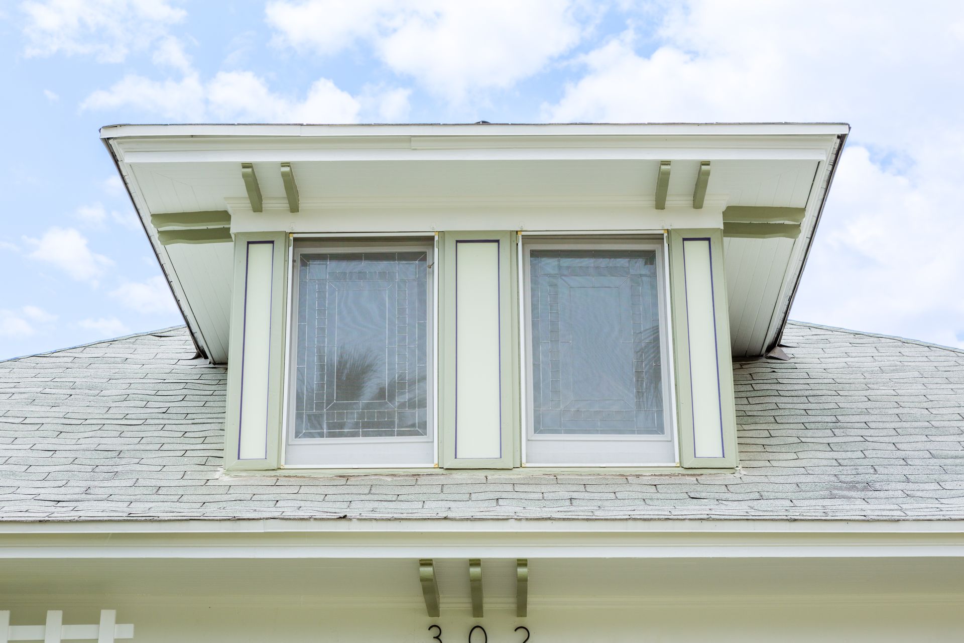 A white house with two windows on the roof and a blue sky in the background.