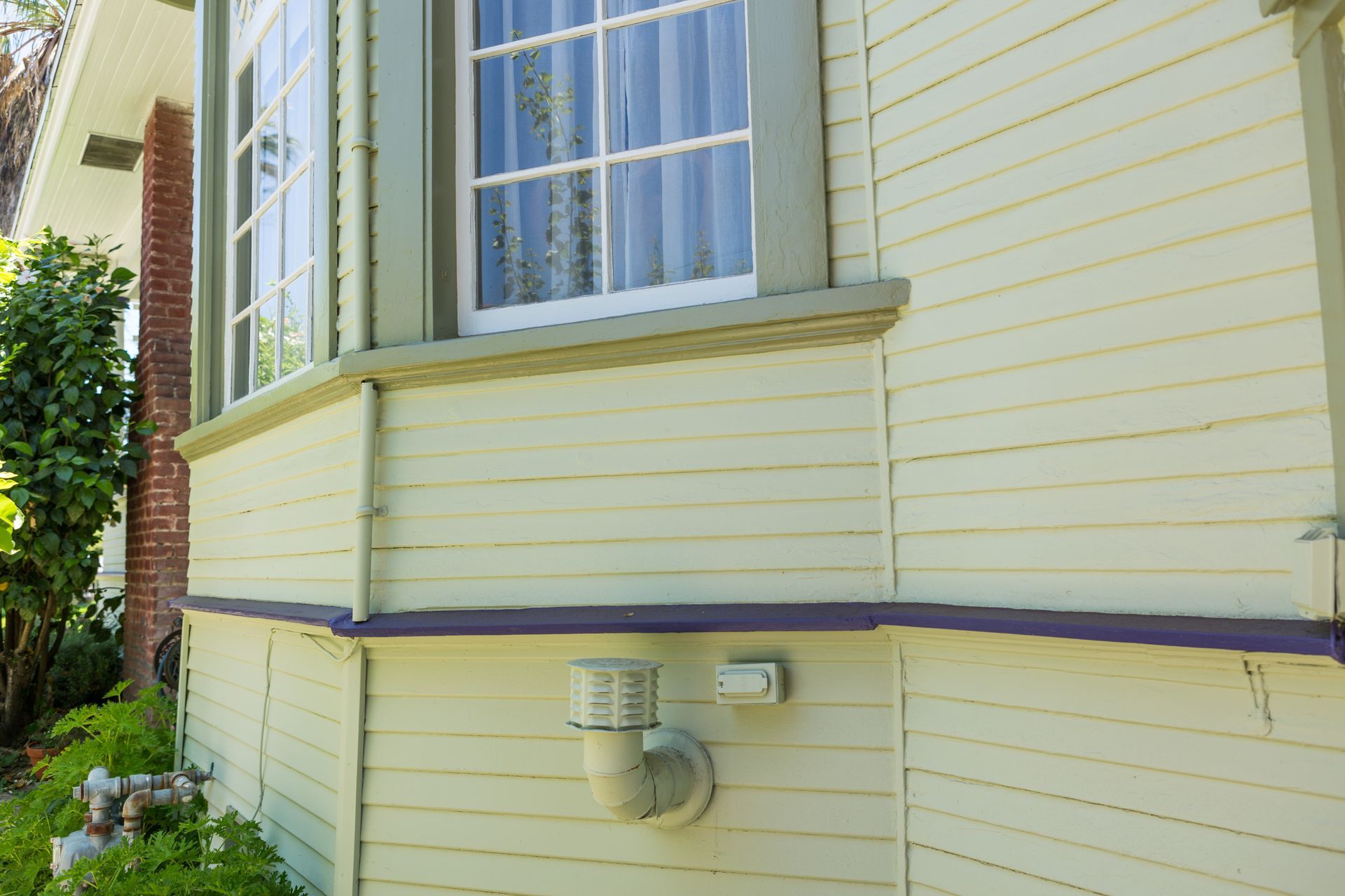 The side of a house with a window and a light on it.
