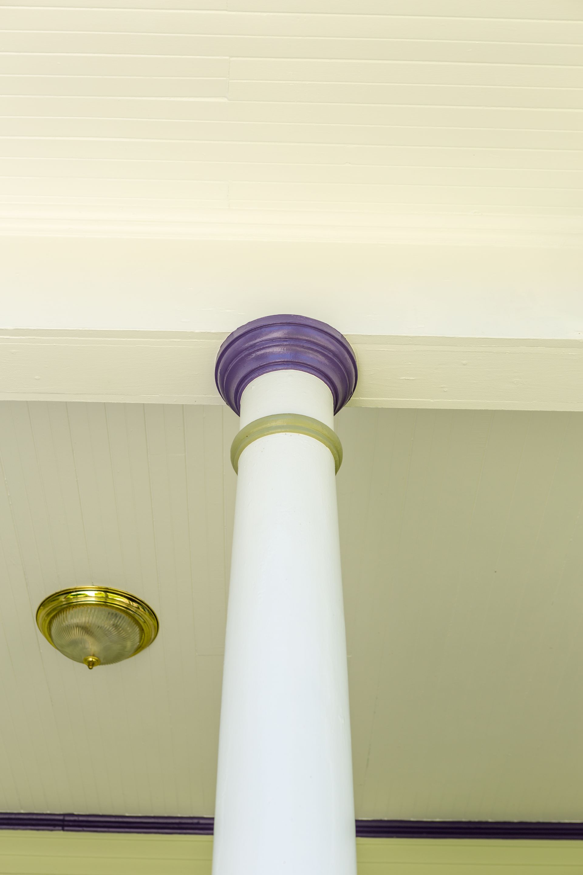 A white column with a purple top and a light on the ceiling