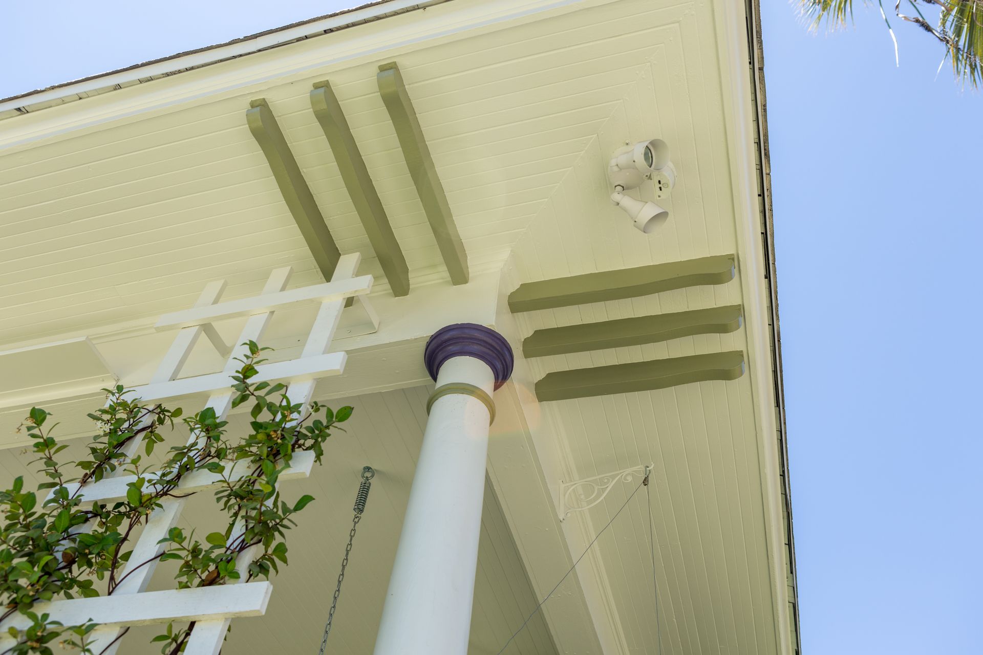 A white porch with a purple column and a white lattice