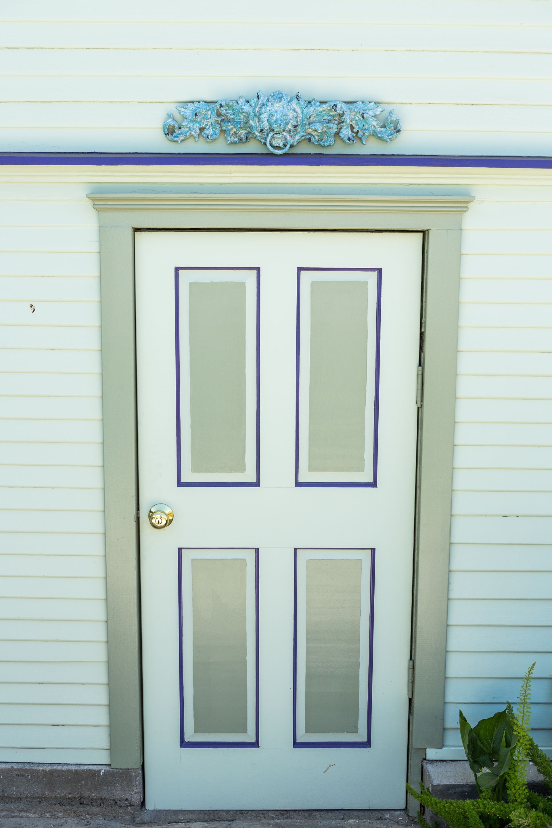 A white door with purple trim is on a white house