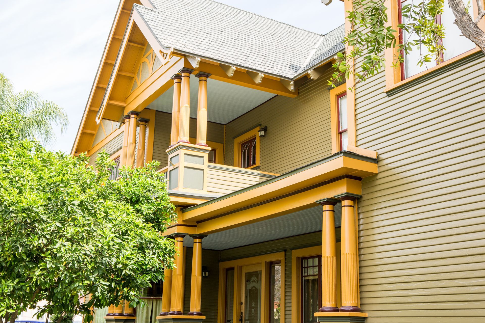 A large house with a large porch and trees in front of it.