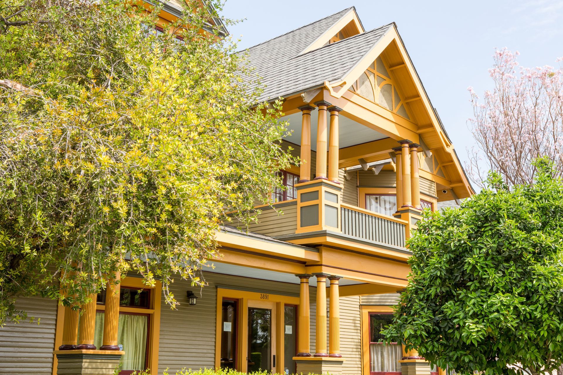 A large house with a porch and trees in front of it.