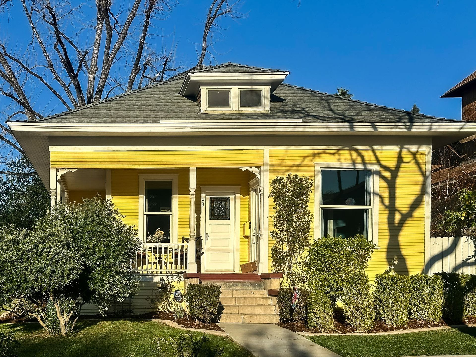 A small yellow house with a porch and stairs