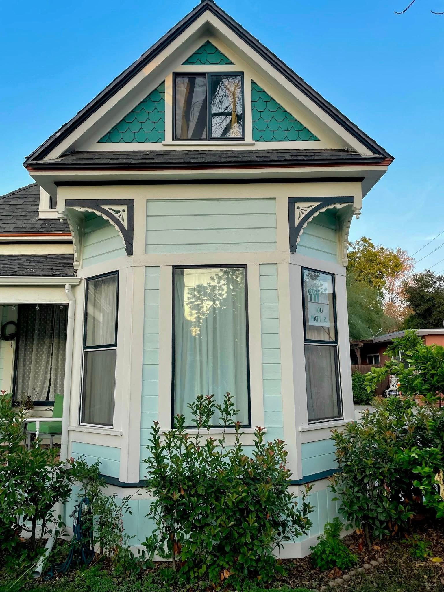 A small blue and white house with a green roof