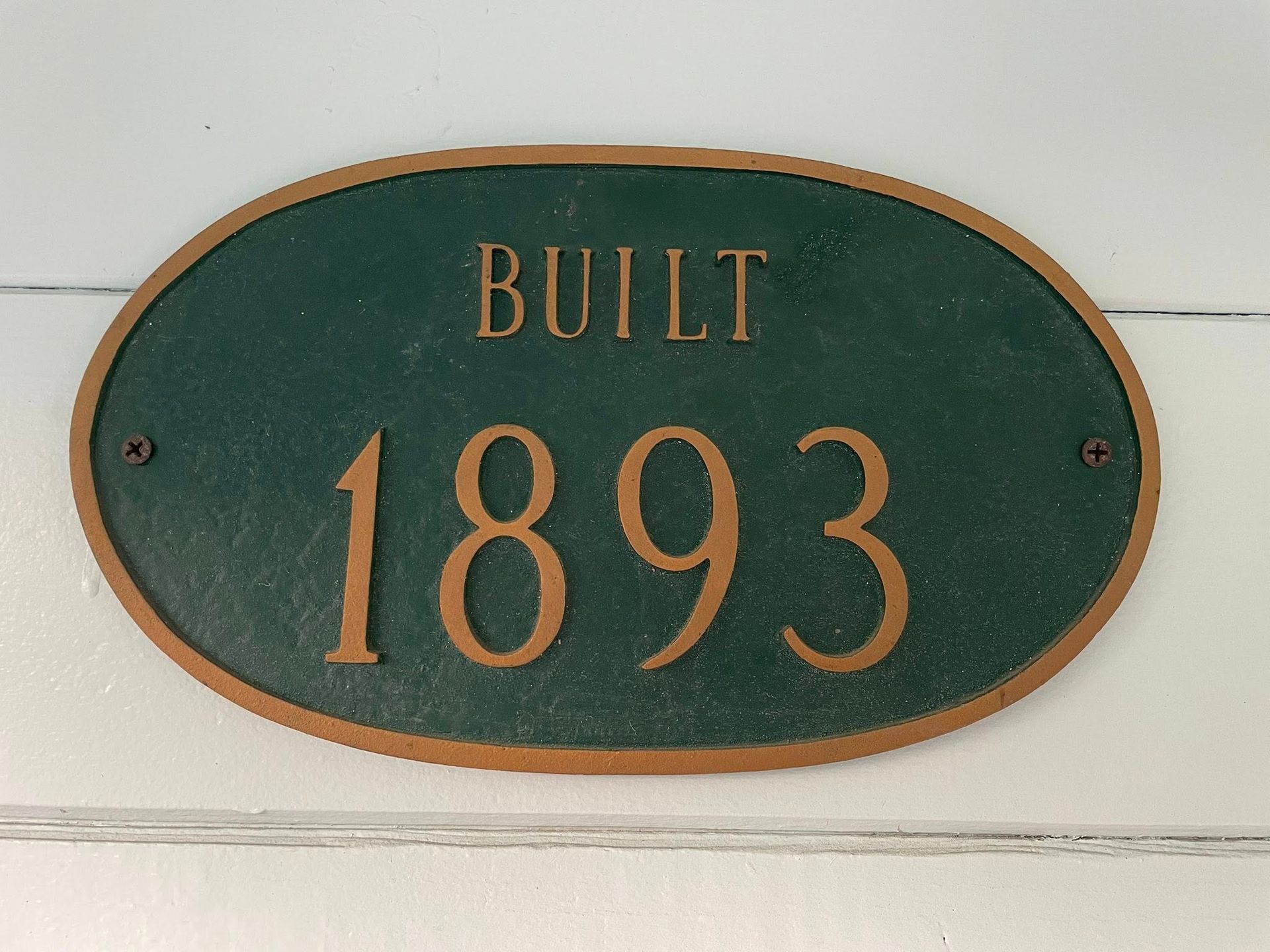 A green sign that says built 1893 on it