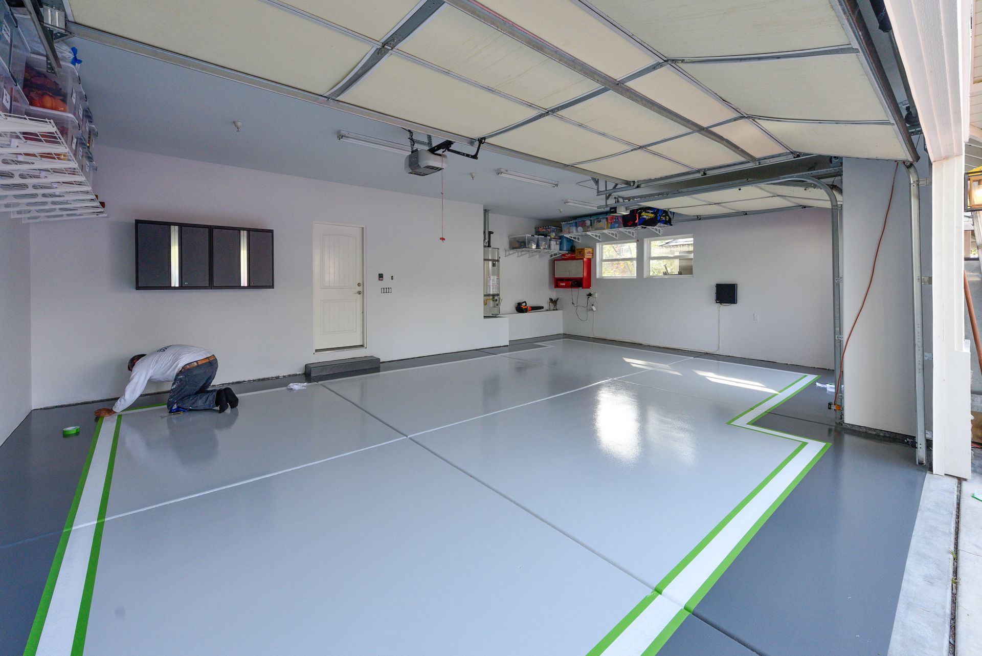 A man is painting epoxy floor of a garage in Redlands, CA.