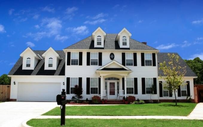 A large white house with black shutters and a mailbox in front of it