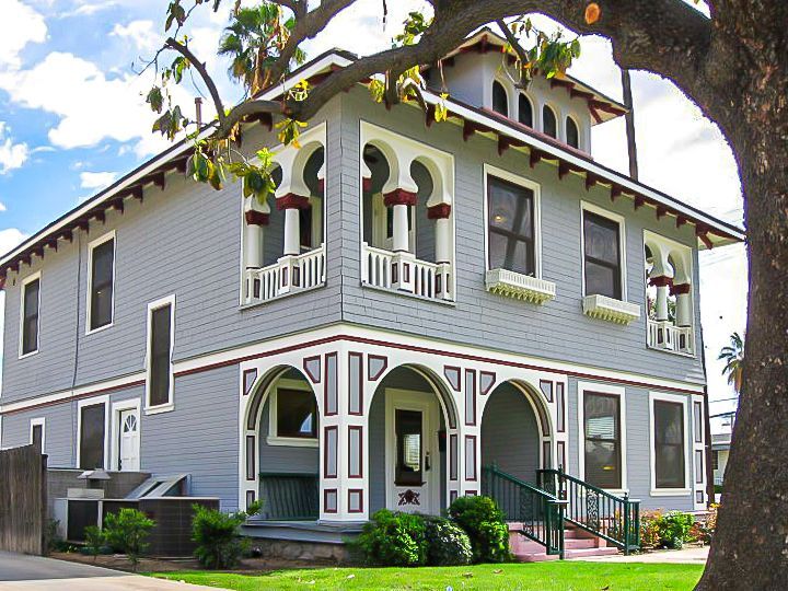 A large grey house with a tree in front of it
