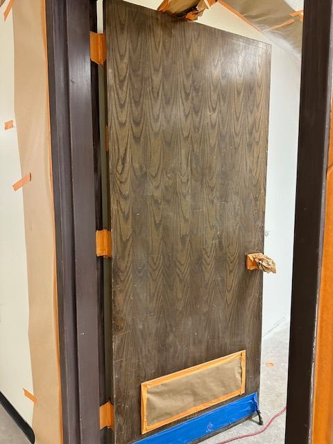 A wooden door is being painted in a room.