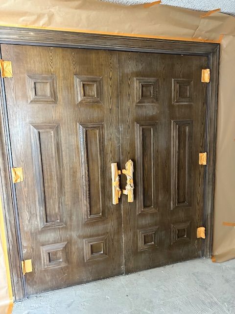 A large wooden door is being painted in a room.
