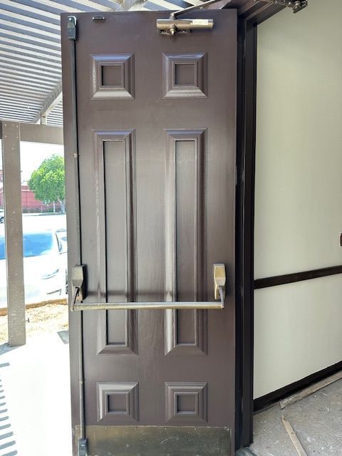 A brown door with a panic bar attached to it