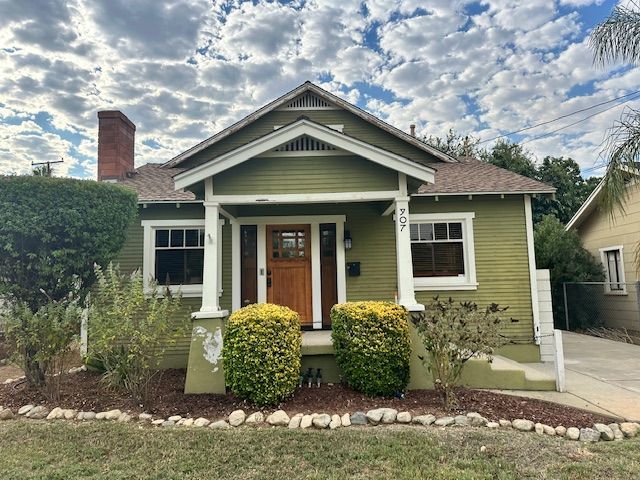 A green house with a porch and a brown door