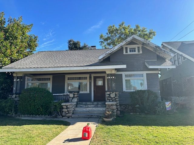 A gas can is sitting on the sidewalk in front of a house.
