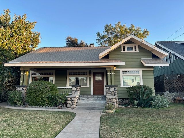 A green house with a brown door and a gray roof