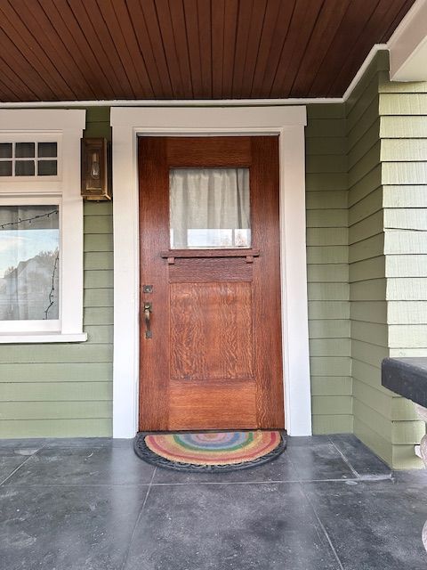 A brown door with a rainbow rug in front of it
