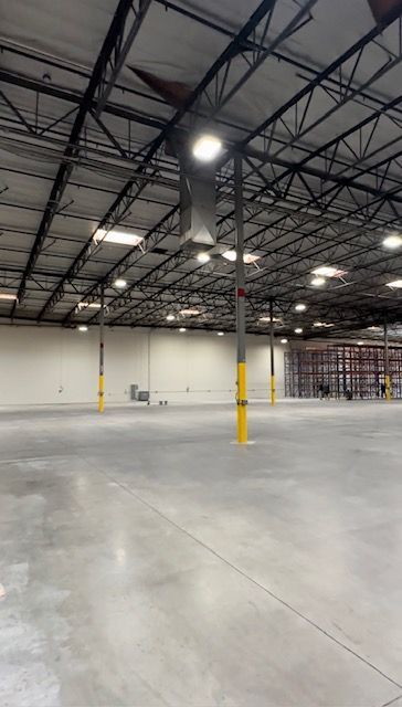 An empty warehouse with a concrete floor and a metal roof